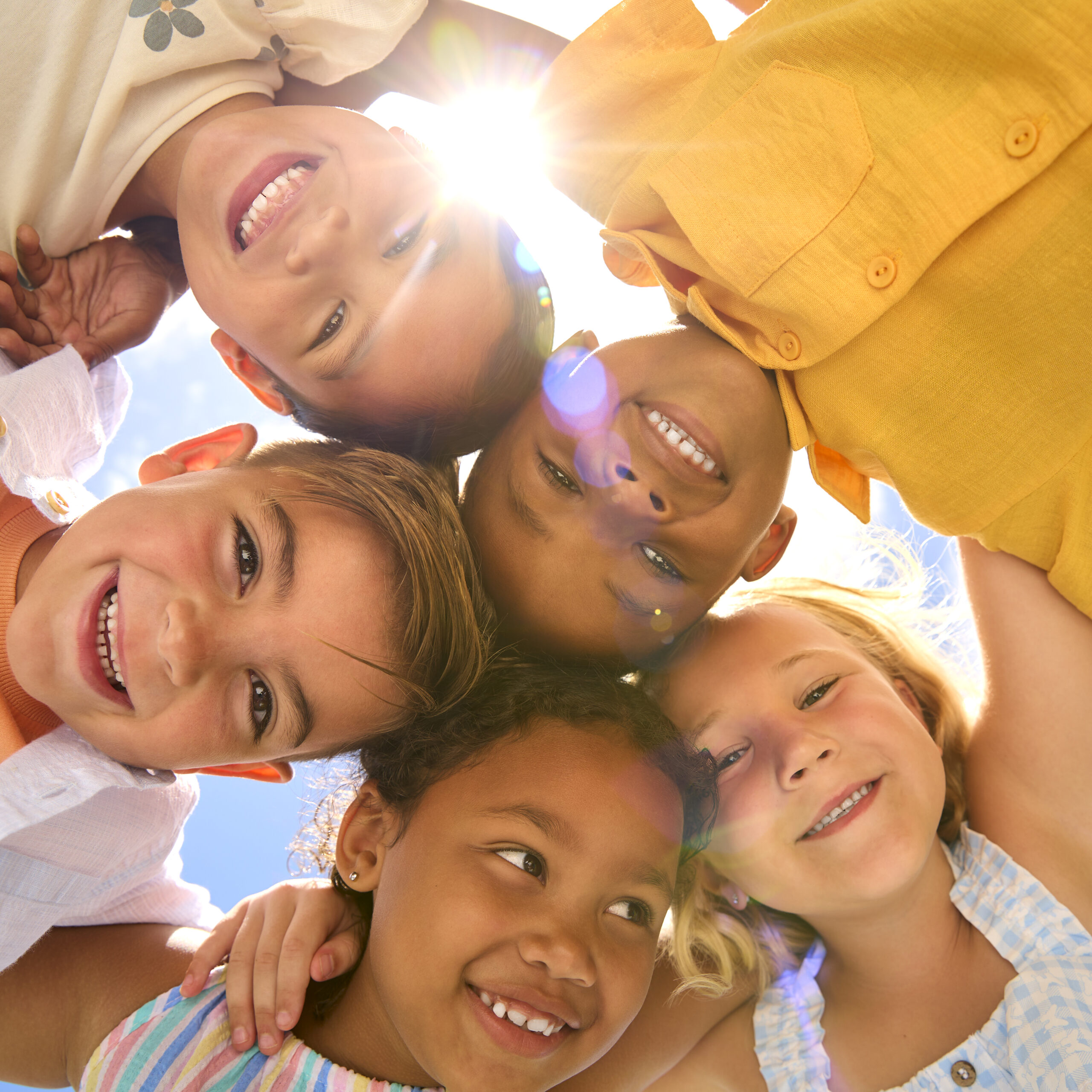 group of multi cultural children friends linking arms looking down into camera